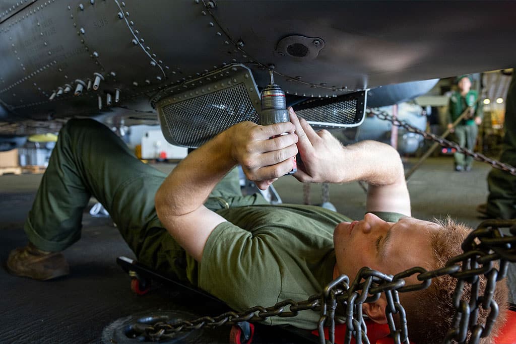 A U.S. Marine conducts maintenance on an AH-1Z Viper in the hangar bay of the amphibious assault ship USS Boxer (LHD 4).