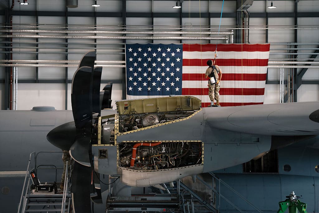 A U.S. Air Force airman is harnessed to the top of a C-130J Super Hercules to conduct letter-check repairs at Ramstein Air Base, Germany.