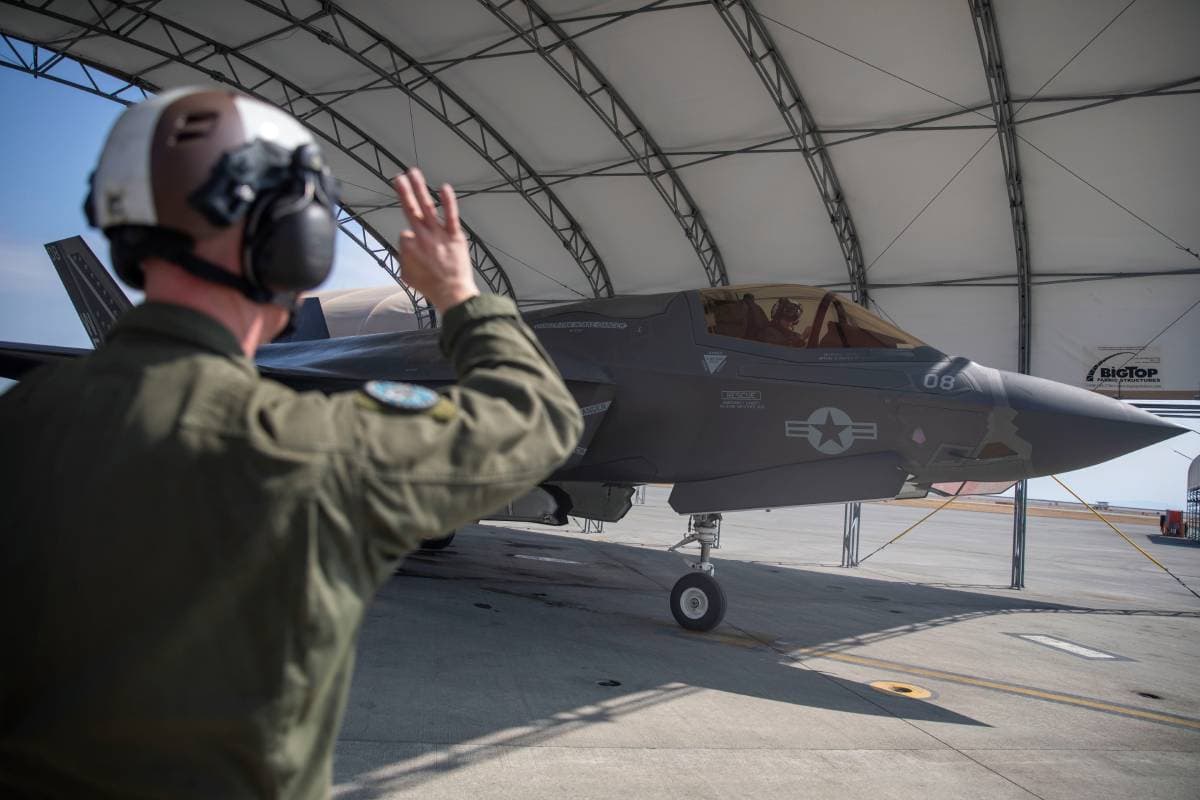 A Marine Corps power line mechanic signaling an F-35B Lightning II on the flight line during post-flight procedures